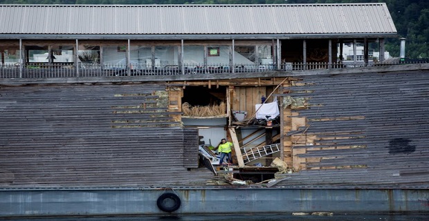 A crew member inspects damages on the hull of a full-size replica of the Ark of Noah after it crashed into a moored coast guard vessel in Oslo harbour