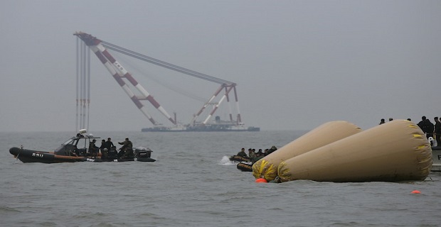 Rescue workers operate near floats where the capsized passenger ship "Sewol" sank, during the rescue operation as a giant offshore crane, which will take part in the rescue operation, is seen in the background in the sea off Jindo April 19, 2014. Divers searching for survivors of a capsized South Korean ferry saw three bodies floating through a window of a passenger cabin on Saturday but were unable to retrieve them, the coastguard said, hours after the ship's captain was arrested. REUTERS/Issei Kato (SOUTH KOREA - Tags: DISASTER MARITIME)